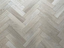 Light herringbone engineered wood flooring with visible grain on rectangular planks
