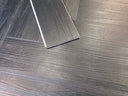 Dark gray wood-look vinyl plank flooring with pale underlay edge