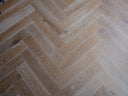 Smoked white engineered herringbone wood floor with varied grain and angled planks