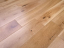 Lacquered solid wood plank flooring in light oak tone with a few darker knot marks