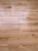 Lacquered solid wood plank flooring, light oak tone with mixed plank widths and knots