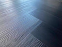 Black and gray wood-look vinyl flooring planks with herringbone texture
