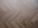 Smoked white engineered herringbone wood flooring in repeating chevron pattern