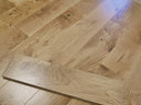 Lacquered solid wood flooring plank with beveled edges, light oak tone and knots